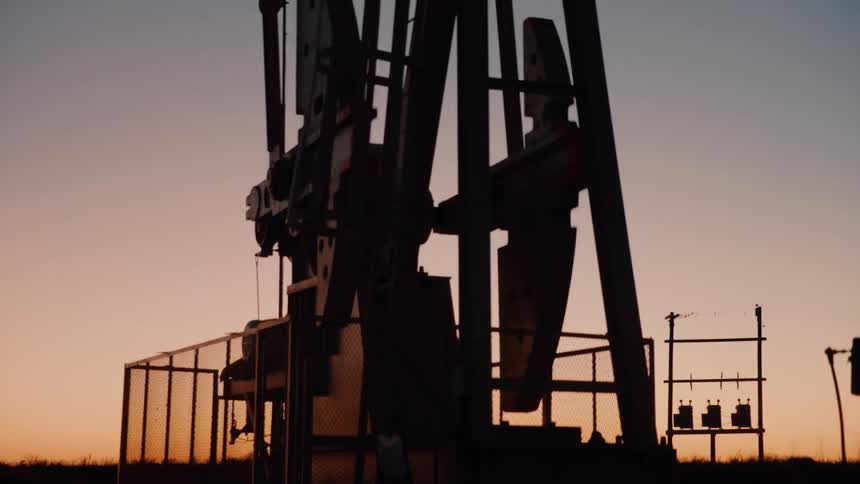 Pump jack against a natural landscape outdoors during dusk or dawn