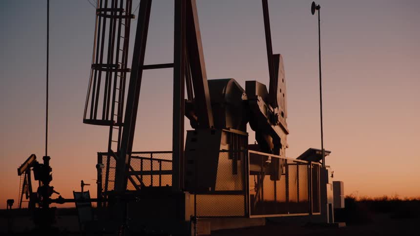 Oil pumpjack silhouette against sunset sky