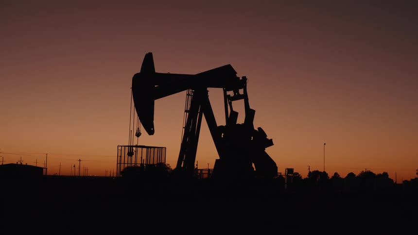 Oil pumpjack silhouette against an orange sunset sky