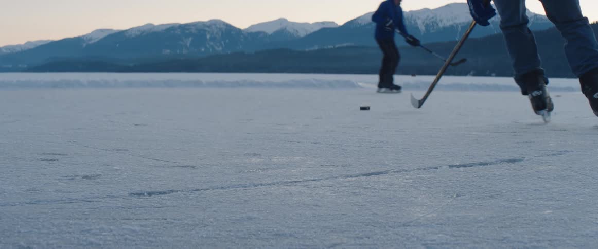 The hockey players speed around the frozen lake playing a sport