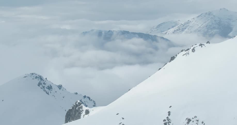 Snow covered mountains are visible with clouds moving through the valleys