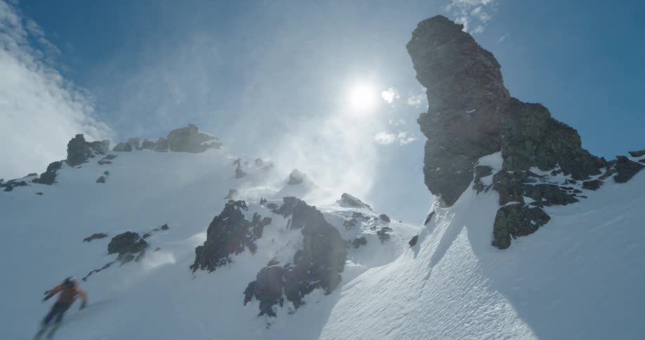 Skier descending steep slope between snowy peaks