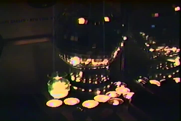 In a dimly lit room a shimmering disco ball and glass orbs sit atop a table surrounded by glowing tea lights their flickering warmth reflecting across polished surfaces in the style of a vintage home movie