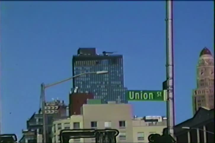 A street sign shows in front of a skyscraper with a crane
