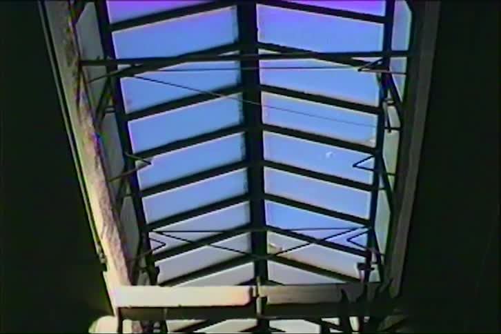 Metal roof structure with exposed beams against a blue sky