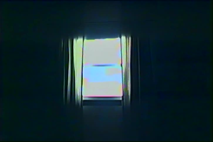 Bright light shines through a small rectangular window with thin curtains in a dark room with a vhs texture distortion