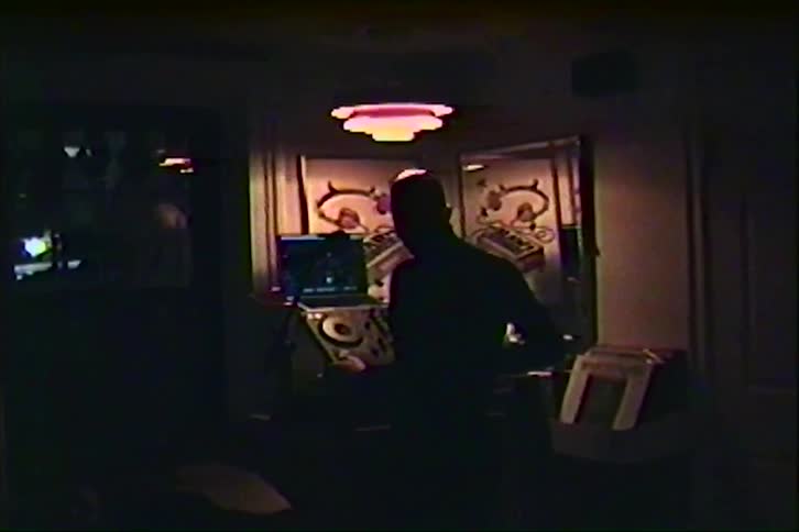 Silhouette of a person in a dark room with illuminated electronic equipment in the background