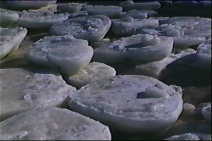 A close view shows many large round pieces of white ice floating in dark water