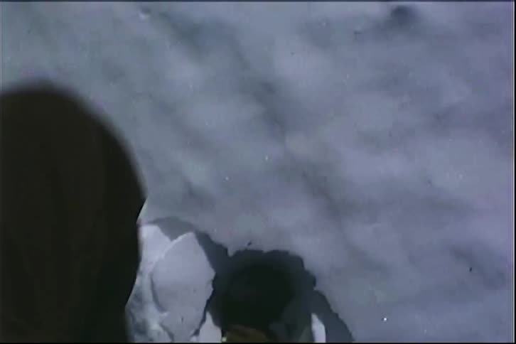 A person wearing boots walking on the snow as it cracks beneath their feet in daylight