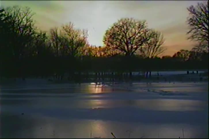 Ice on a pond in the woods under a cloudy sky at dusk