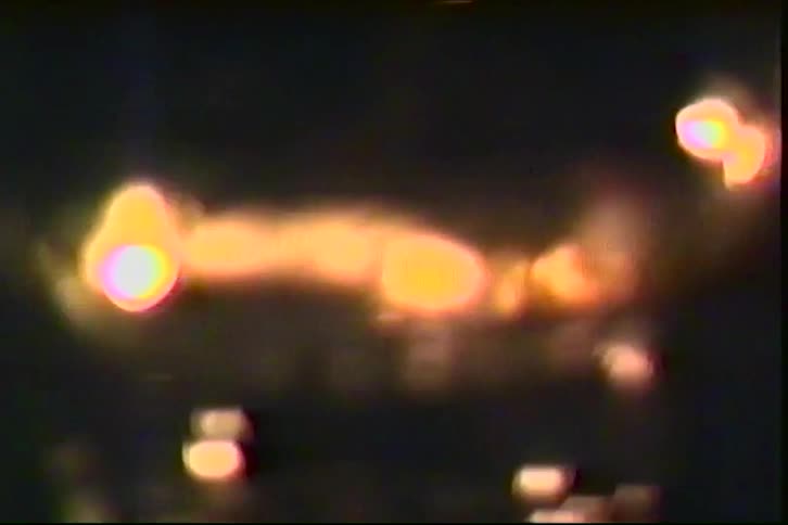 A close view of several small round candles flickering with warm orange light in a dark room with a grainy film texture and soft bokeh effects