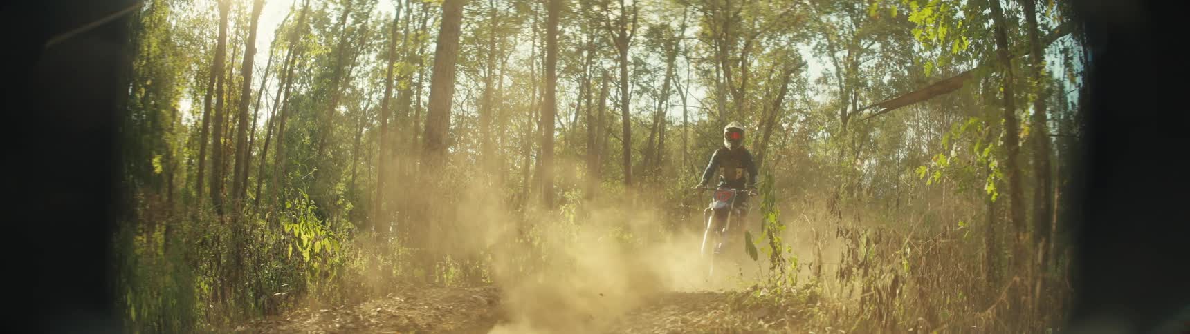 The two men race through the forest on dirt bikes