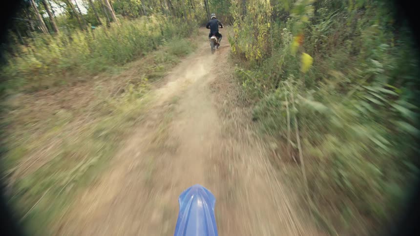 Two people riding dirt bikes outdoors
