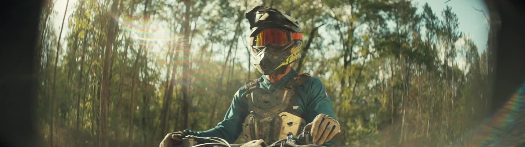 A person wearing a crash helmet and goggles pauses atop a dirt bike