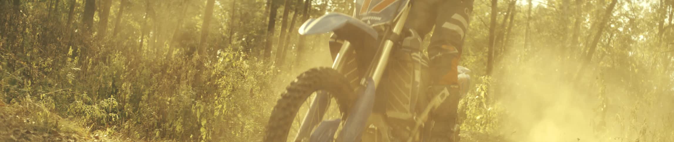 The dirt bike races through dust clouds in the forest