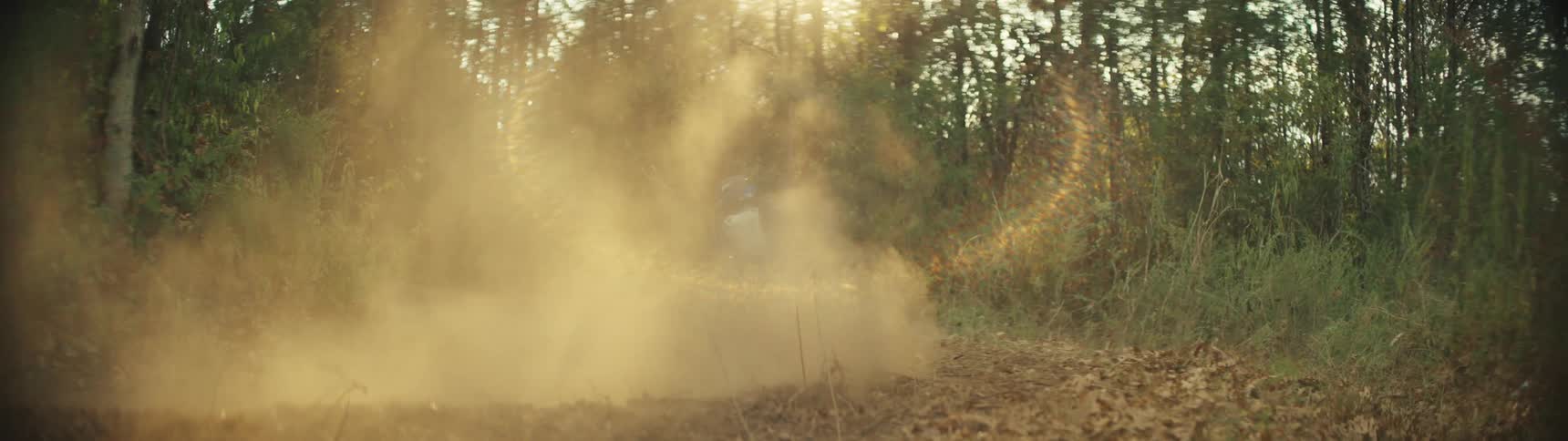 A person rides a dirt bike on a forested trail