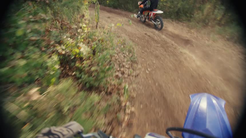 Two people race and jump on the trail with their dirt bikes