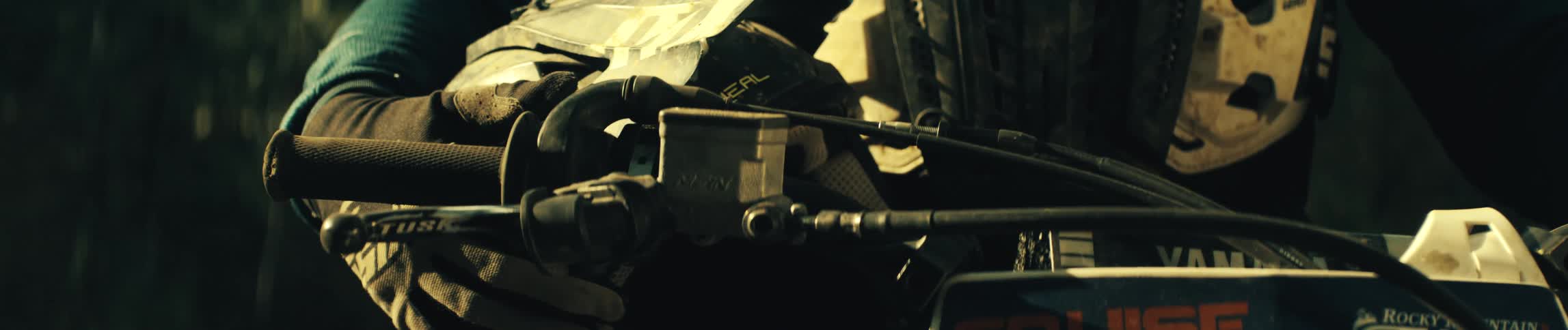A gloved hand operates the throttle and brake lever of a dirt bike