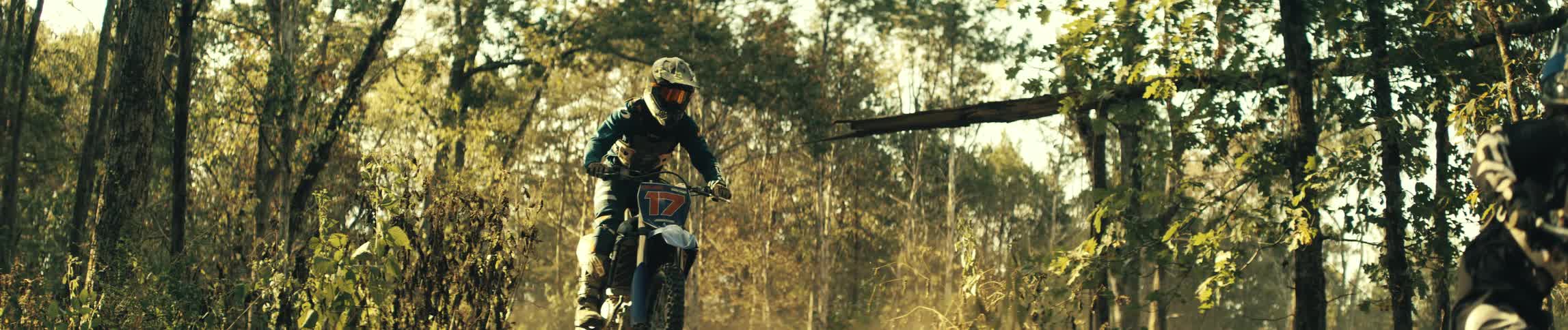 Two people jumping dirt bikes outdoors