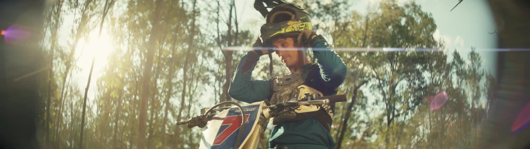 Man sits on a motorcycle as he puts on his helmet