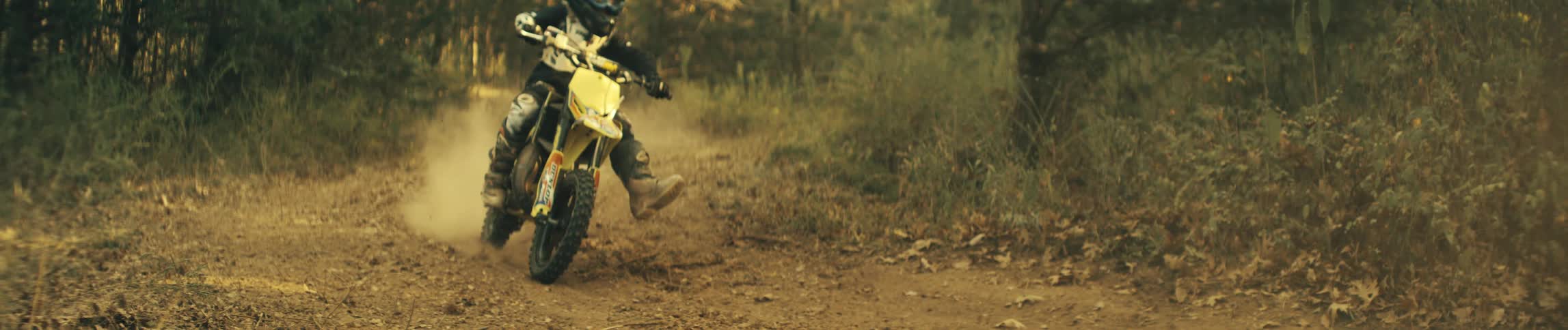 Rider maneuvering yellow dirt bike on trail