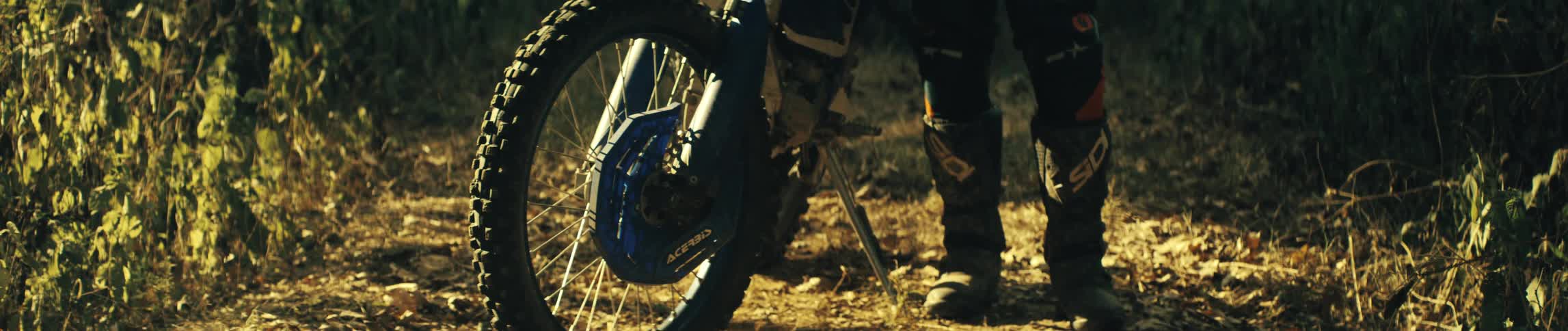 A mountain biker standing beside his parked bike in the woods at midday
