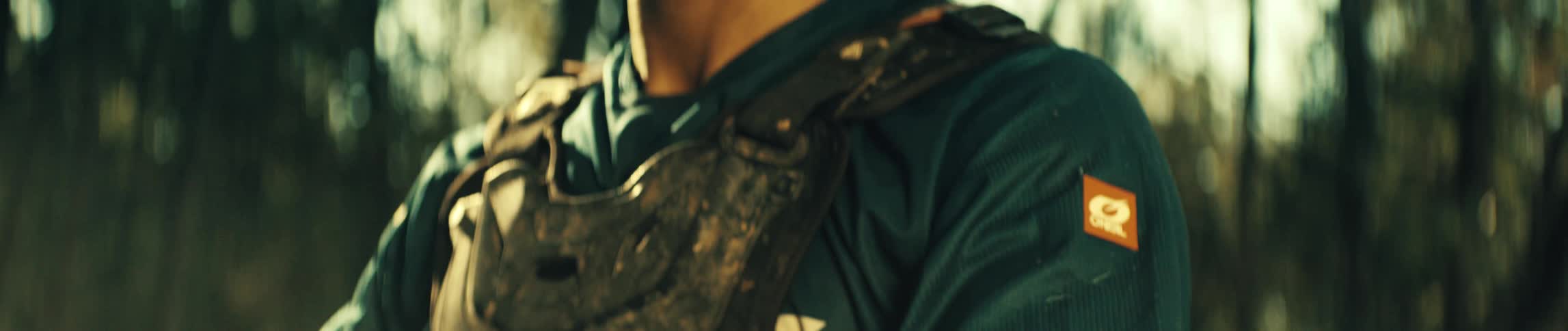 A man sitting on a dirt bike gazes upward in a softly blurred forest warm golden sunlight illuminating his face
