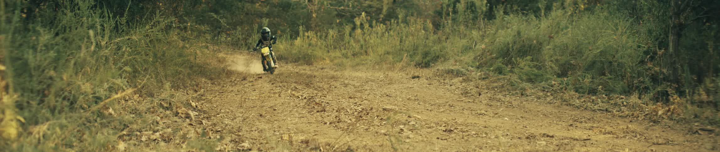 A person drives a dirt bike along a trail at a high rate of speed
