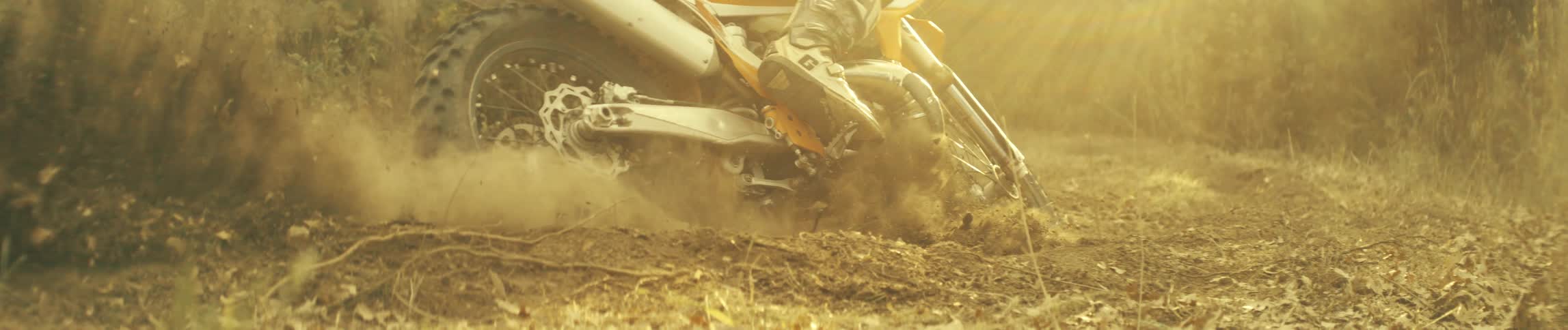 A person on a dirt bike takes a sharp turn while driving along a trail