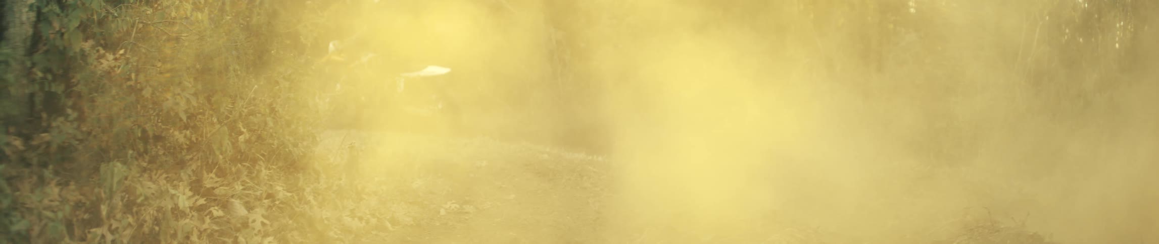 Motorcyclist passing by and leaving a cloud of dust