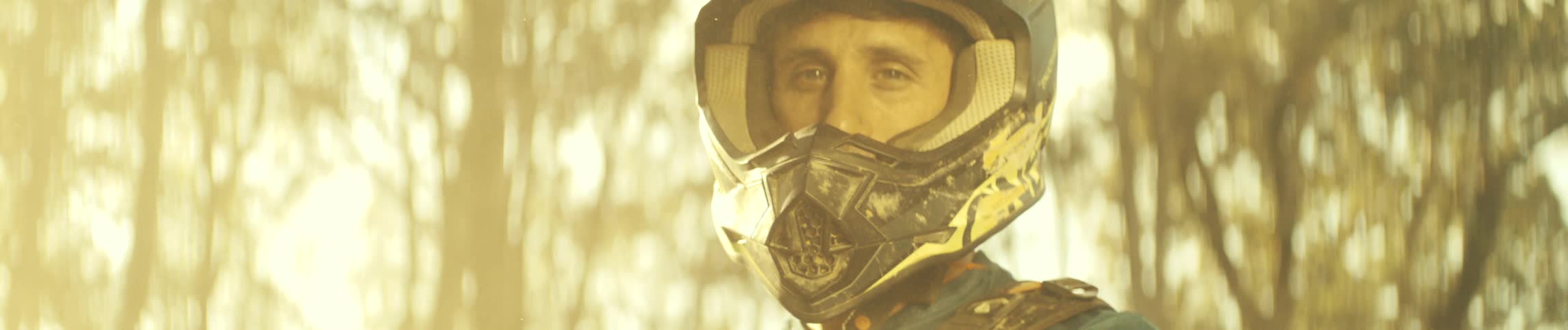 A mountain biker wearing a helmet removes his goggles revealing his face while keeping the helmet on on a sunny day