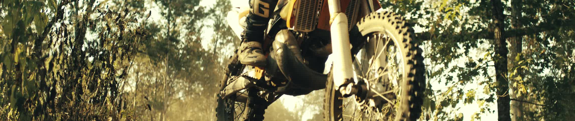 Motocross biker wearing a helmet riding a motorcycle near a forest outdoors during day time