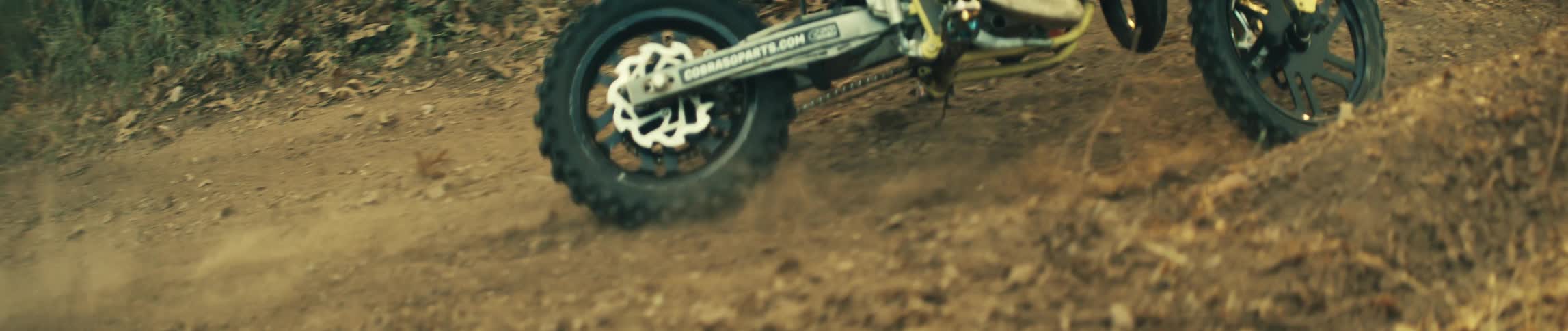 A mountain biker riding through the woods dust flying behind him as he takes a curve