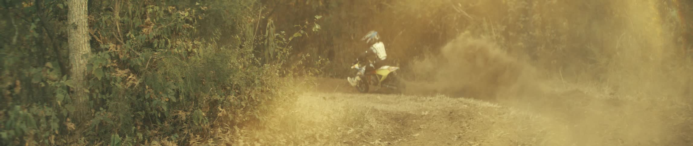 A man is riding a motorcycle on a dirt road