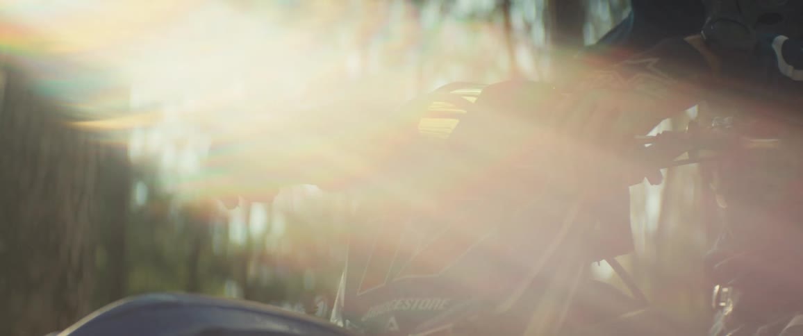 The sun is flaring on the person sitting on a dirt bike