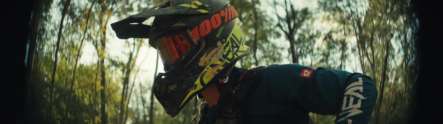 The person is riding their dirt bike in the woods on a sunny day