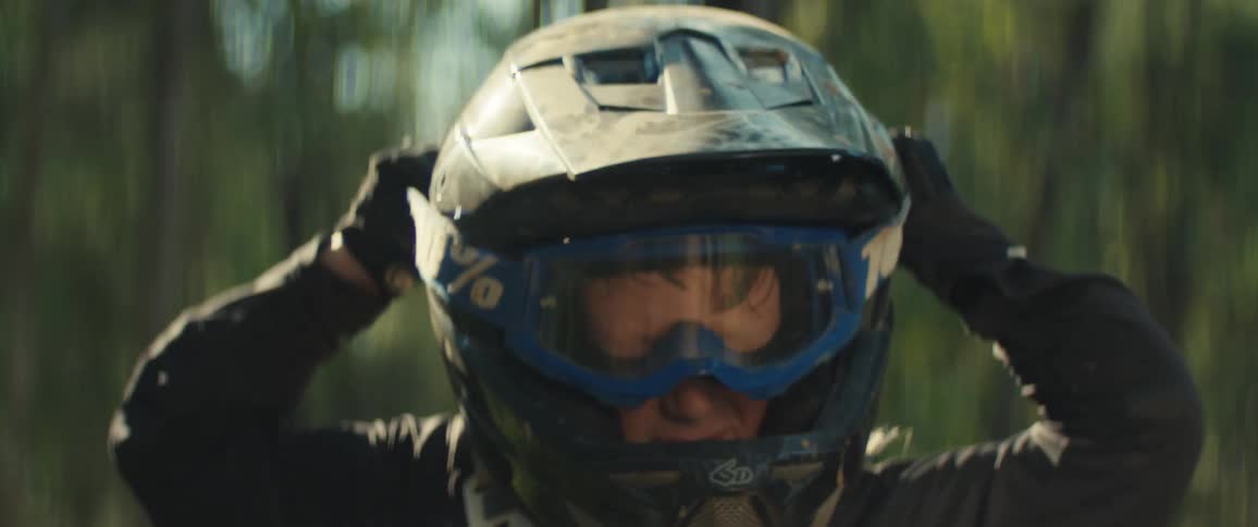 Boy puts on a motocross helmet while wearing a chest protector outdoors