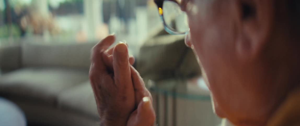 A close up of an elderly man in a modern living room clapping his hands and cheering