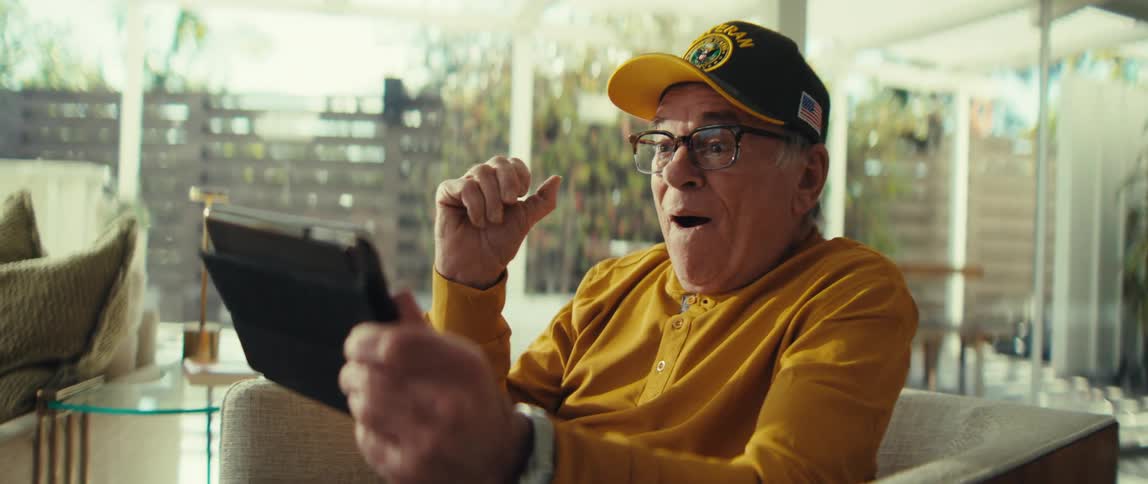 Elderly man cheers while watching a media stream on his tablet during a day at home