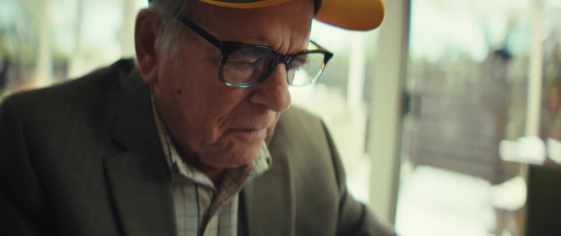 Person adjusting glasses with green and yellow cap