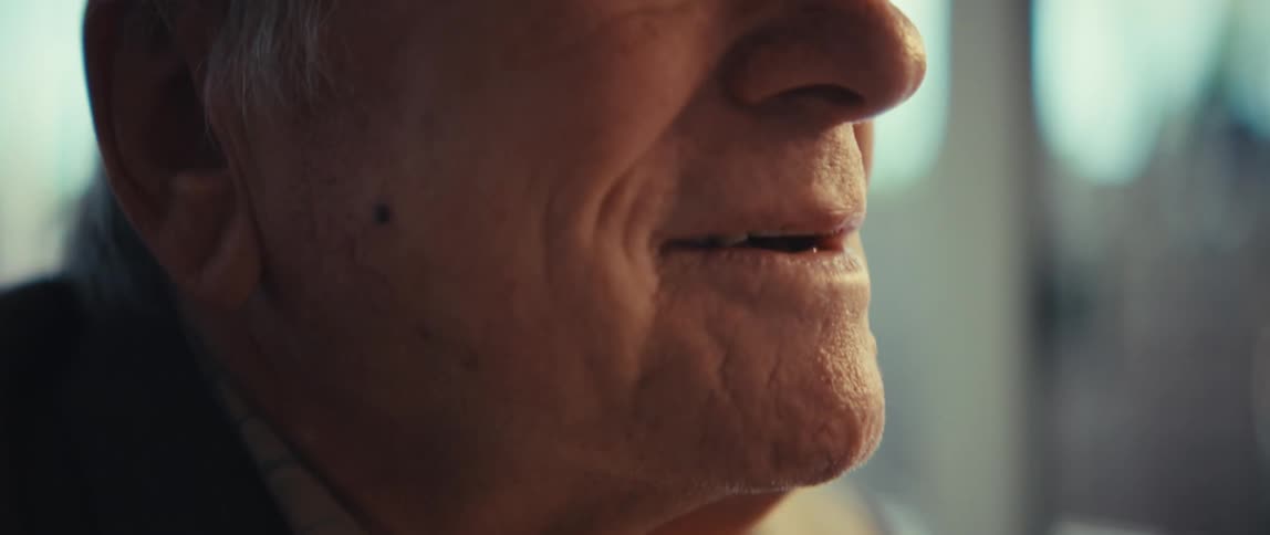 Elderly white man wearing a baseball cap talking indoors during day time