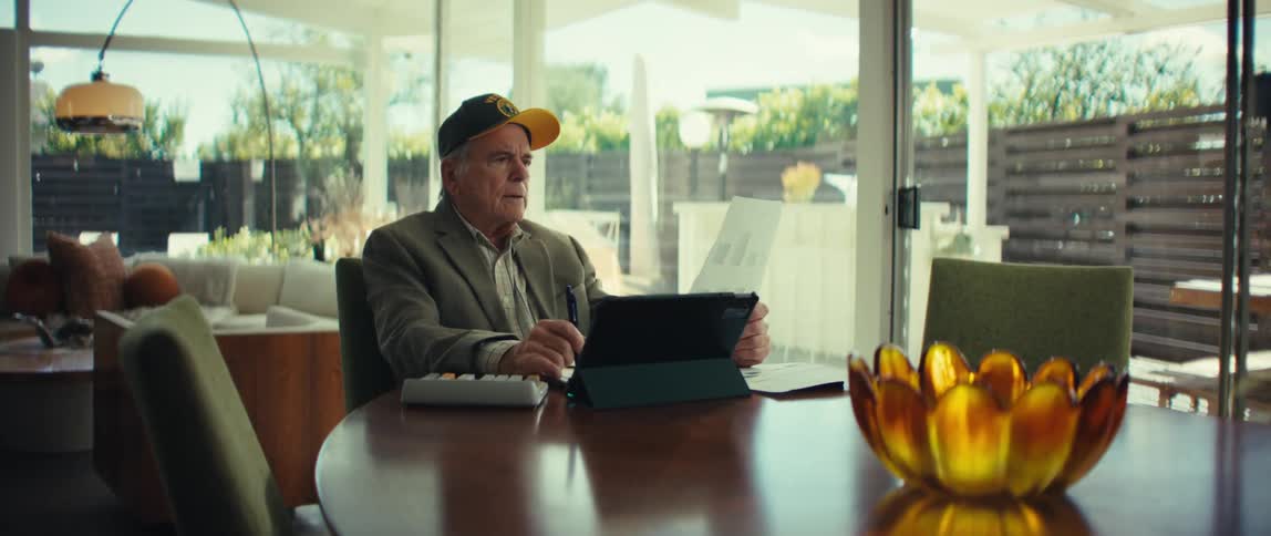A man thinks as he sits at a table in front of a laptop