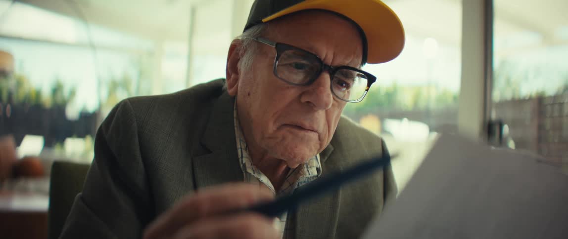 The man is reading and holding a piece of paper