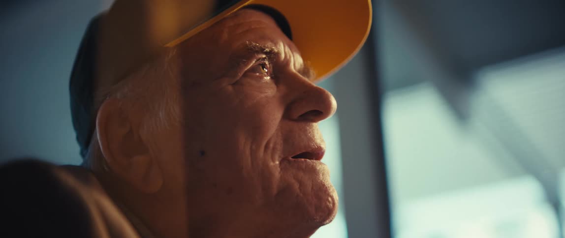 A sad elderly man slowly looks upwards with tears in his eyes
