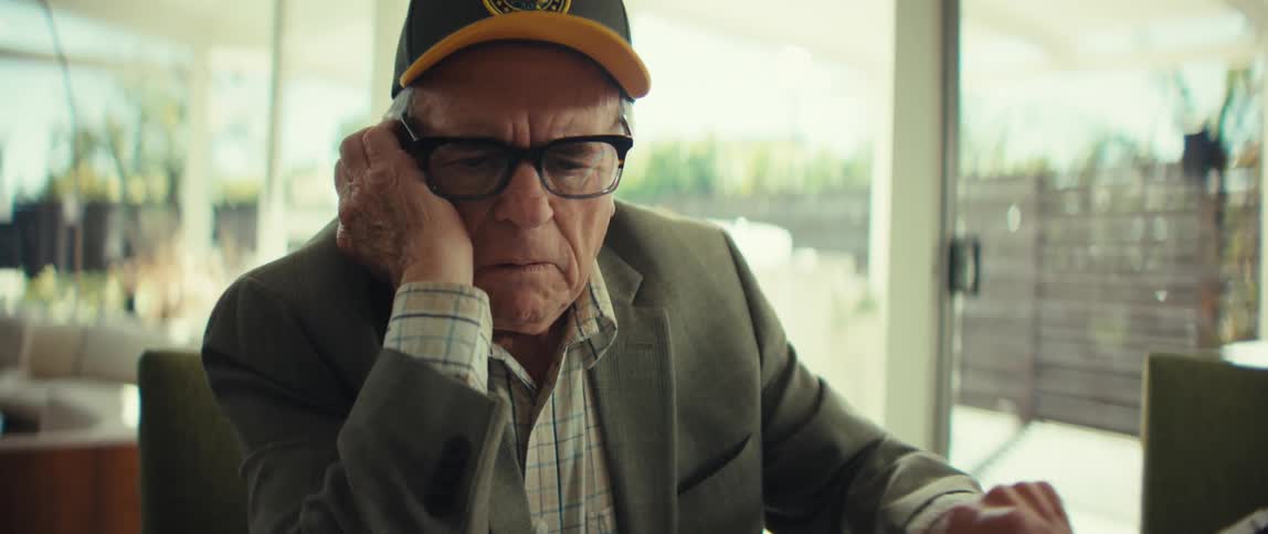 An elderly man uses a calculator and then stop as he worries