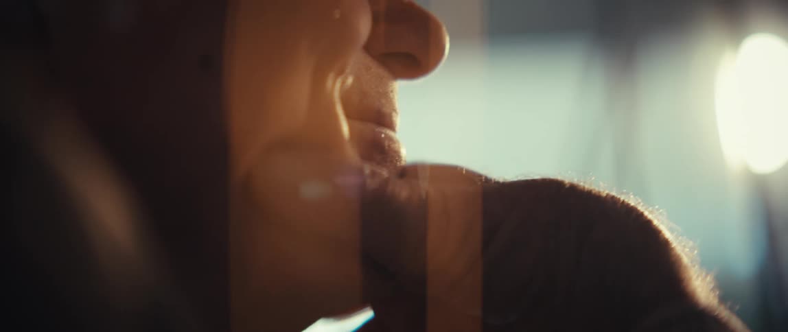 A close view of an elderly veteran shows his face in profile as he smiles while a golden light reflects in his eyes and across his skin
