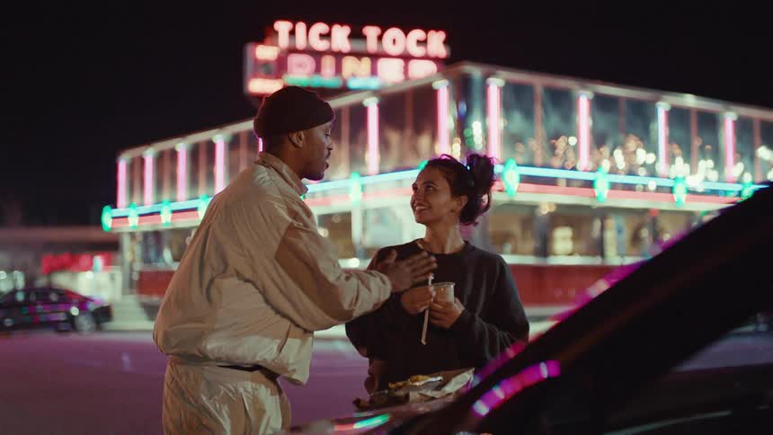 A man is excited as he talks to a woman outside a restaurant