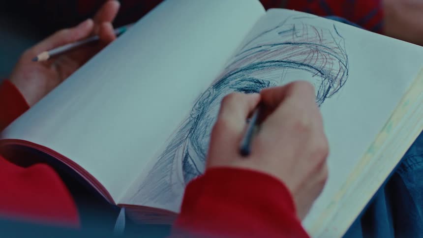 An artist uses a graphite pencil to add detailed shading and depth to a sketch of a persons facethe pencil moves across the paper in a sketchbook focusing on the contours around the eye and bridge of the nose