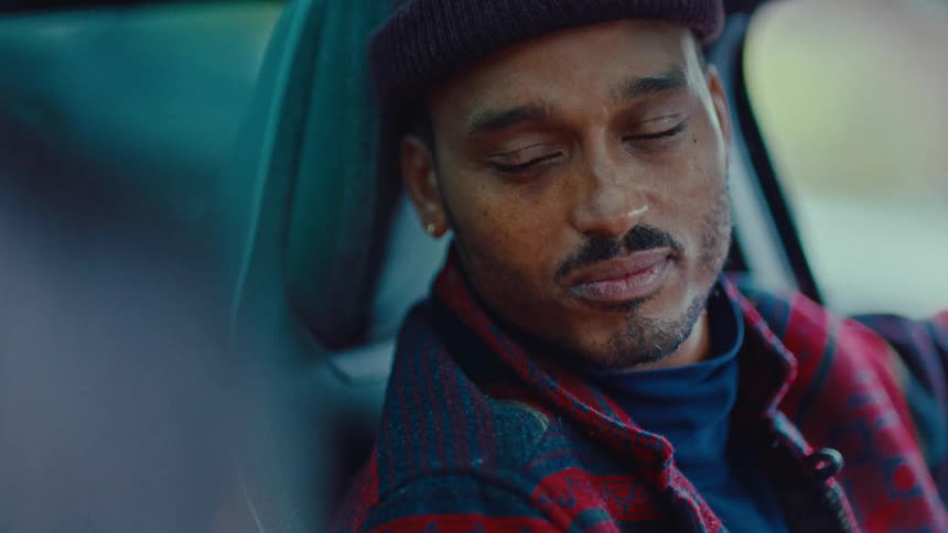 A man sits in the driver seat of a vehicle while watching someone else
