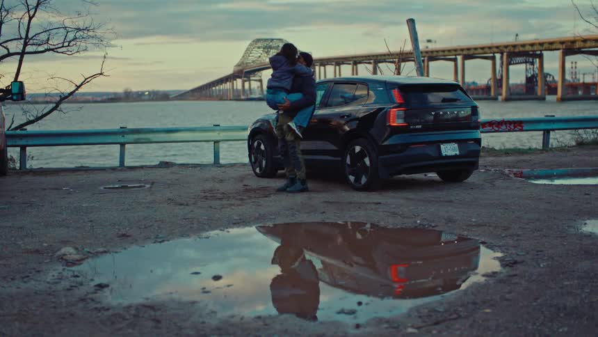 A man and woman hugging each other next to a car